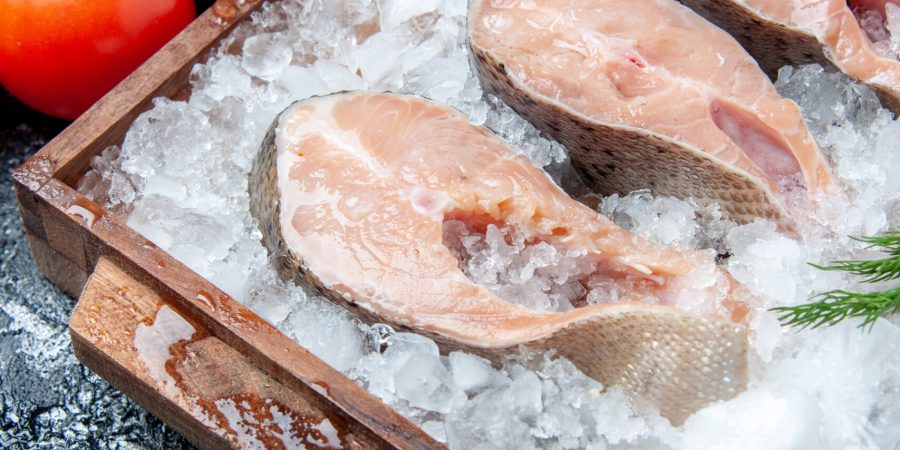 bottom-view-raw-fish-slices-with-ice-wood-board-fresh-tomatoes-table